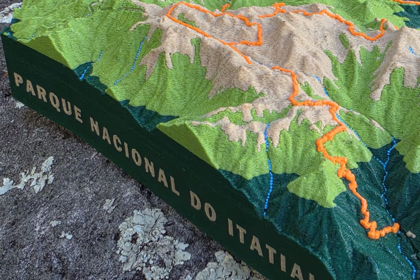 Maquete topográfica do Parque Nacional do Itatiaia apoiada sobre uma rocha, com o relevo e as trilhas em destaque